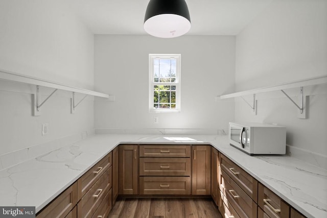 interior space with light stone counters, dark hardwood / wood-style flooring, and kitchen peninsula