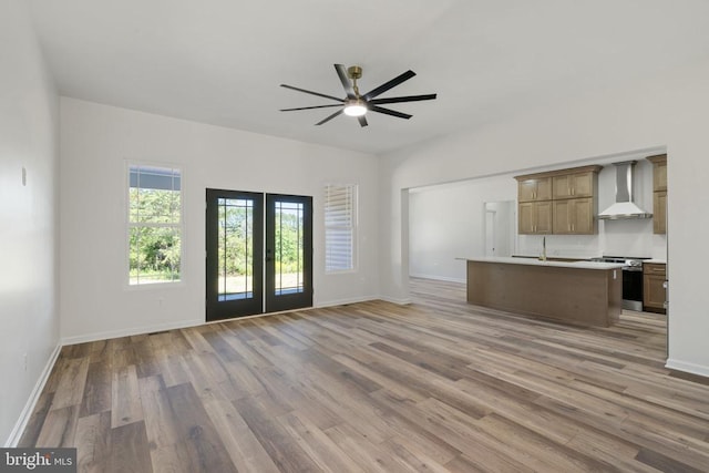 unfurnished living room featuring french doors, a ceiling fan, baseboards, and light wood-style floors