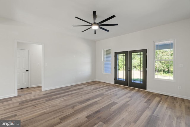 empty room with wood finished floors, baseboards, ceiling fan, and french doors