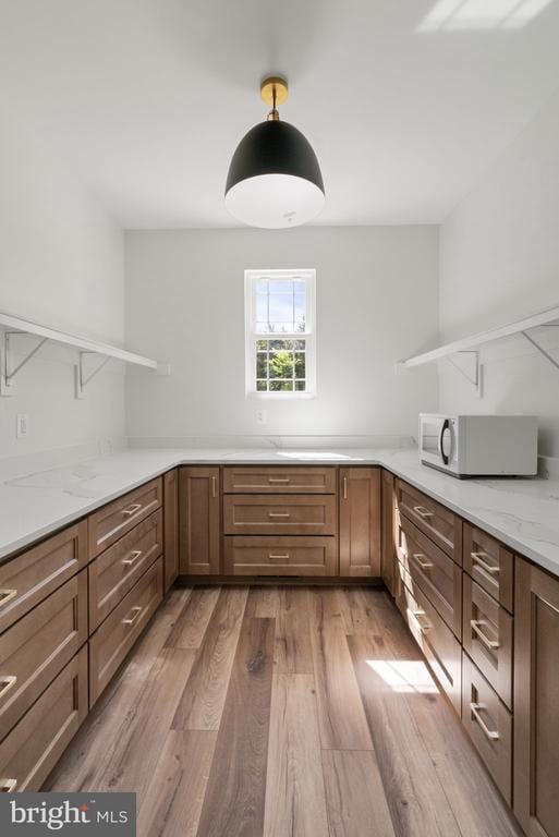 kitchen featuring light stone counters, kitchen peninsula, and light hardwood / wood-style flooring