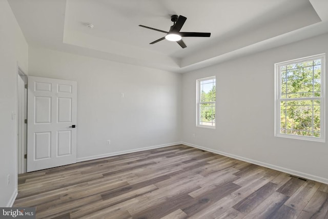 spare room featuring hardwood / wood-style flooring, ceiling fan, and a tray ceiling