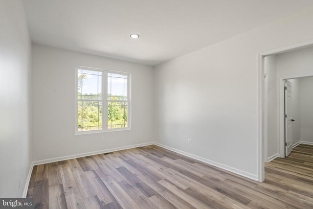 empty room featuring recessed lighting, wood finished floors, and baseboards