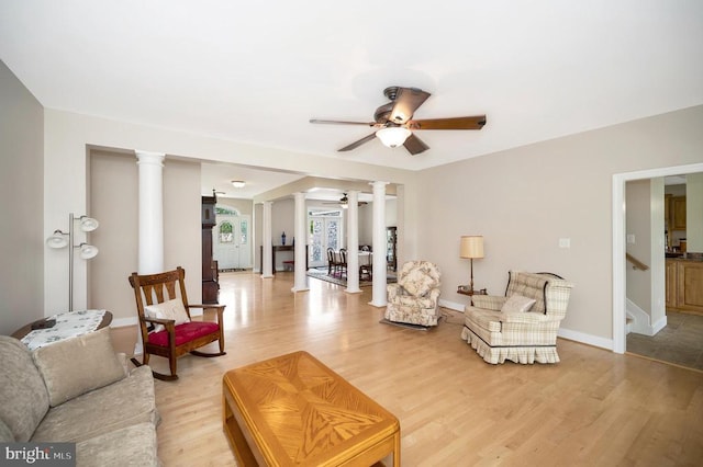 living area with baseboards, light wood-style floors, decorative columns, and a ceiling fan