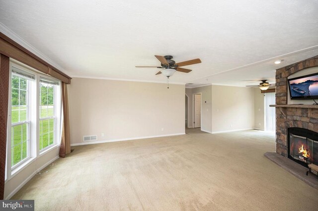 unfurnished living room featuring light colored carpet, a fireplace, visible vents, baseboards, and ornamental molding