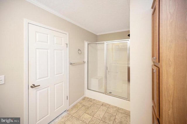 bathroom with a stall shower, crown molding, and baseboards