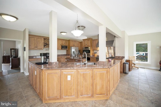 kitchen with a spacious island, appliances with stainless steel finishes, a sink, dark stone counters, and baseboards