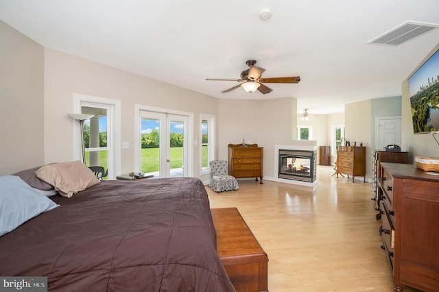 bedroom with visible vents, access to outside, french doors, light wood-type flooring, and a multi sided fireplace