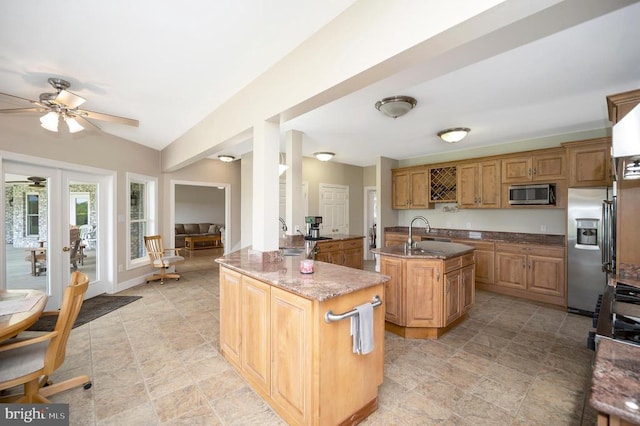 kitchen with stone counters, a kitchen island with sink, stainless steel appliances, a sink, and french doors