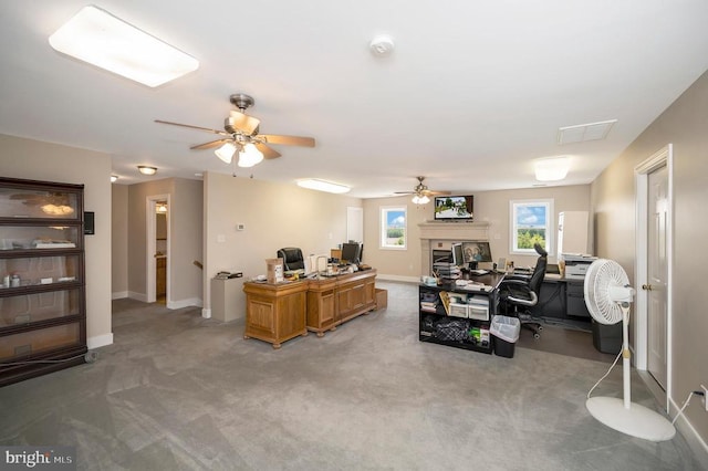 carpeted office with ceiling fan, a fireplace, visible vents, and baseboards