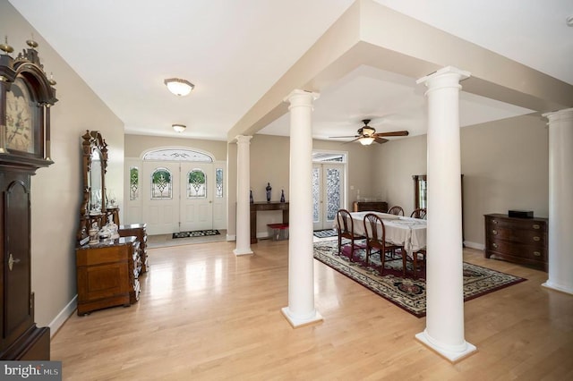 foyer featuring light wood finished floors, plenty of natural light, decorative columns, and a ceiling fan