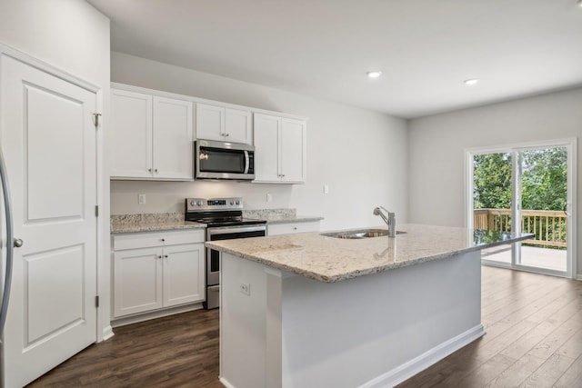 kitchen featuring white cabinetry, sink, stainless steel appliances, light stone countertops, and a center island with sink