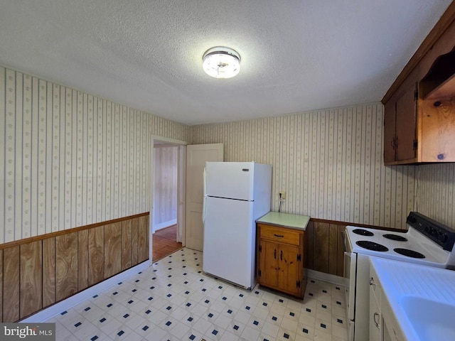 kitchen featuring white appliances, light countertops, wallpapered walls, and light floors