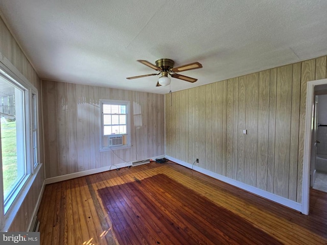 spare room with wood-type flooring, baseboards, a textured ceiling, cooling unit, and a ceiling fan