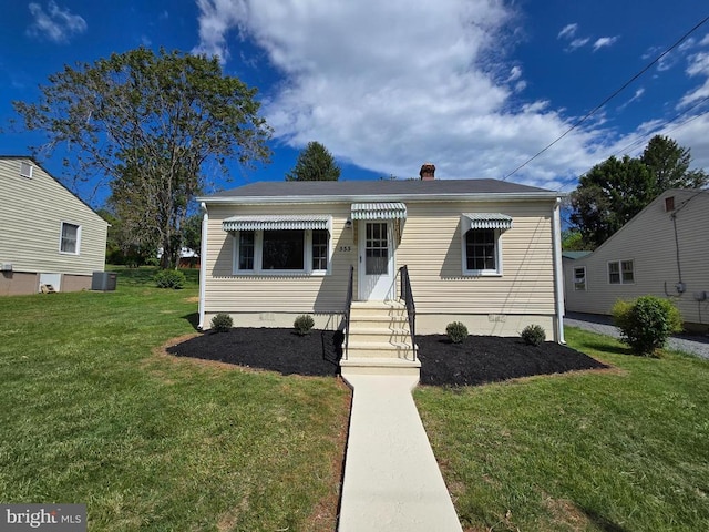 bungalow featuring entry steps, central AC unit, a front yard, and a chimney