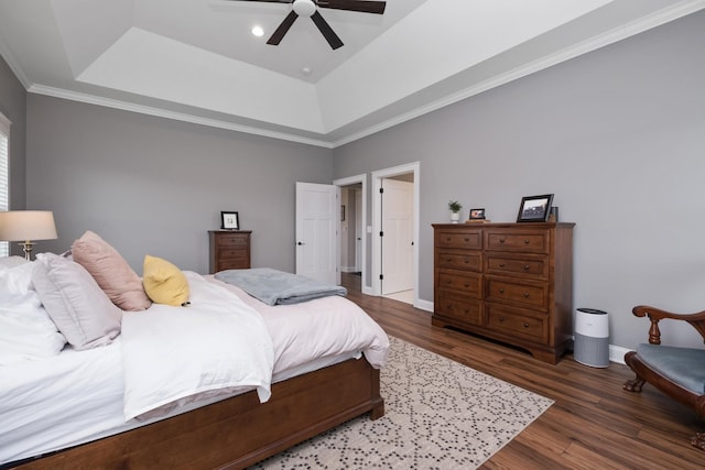 bedroom featuring wood finished floors, ornamental molding, baseboards, a raised ceiling, and a ceiling fan