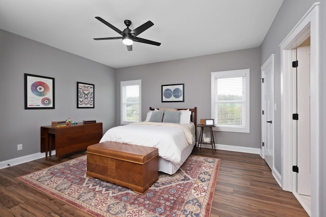 bedroom with dark wood-type flooring, a ceiling fan, and baseboards
