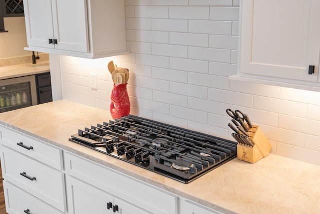 kitchen featuring white cabinets, black cooktop, and decorative backsplash