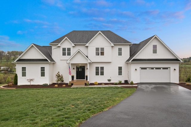 view of front of property with a lawn, roof with shingles, a garage, and aphalt driveway