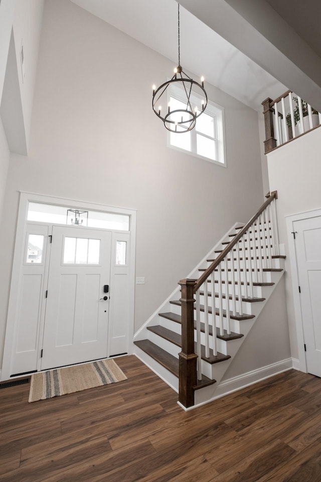 foyer entrance featuring stairs, high vaulted ceiling, an inviting chandelier, and wood finished floors