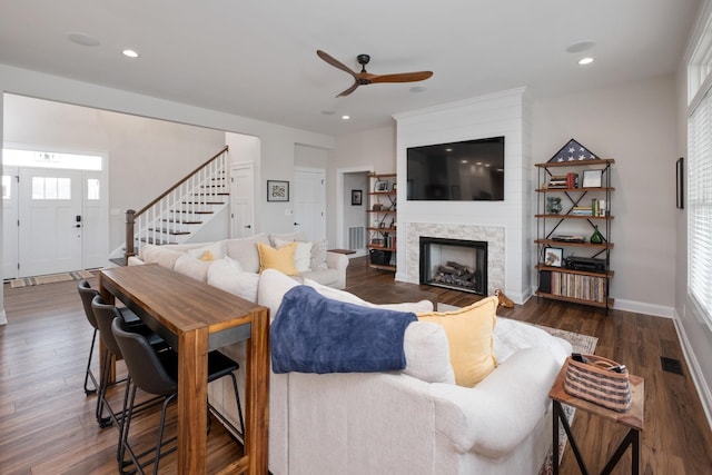 living room with recessed lighting, stairs, ceiling fan, a stone fireplace, and dark wood-style floors