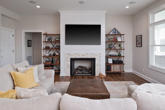 living room with visible vents, baseboards, recessed lighting, a fireplace, and wood finished floors