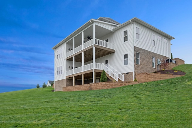 back of house featuring a lawn, ceiling fan, and a balcony