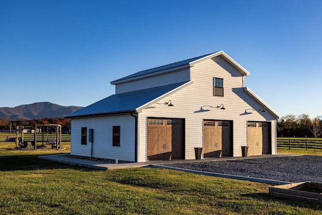 back of house with a garage, an outbuilding, a lawn, and a mountain view