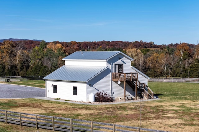 exterior space featuring a rural view, a wooden deck, and a lawn