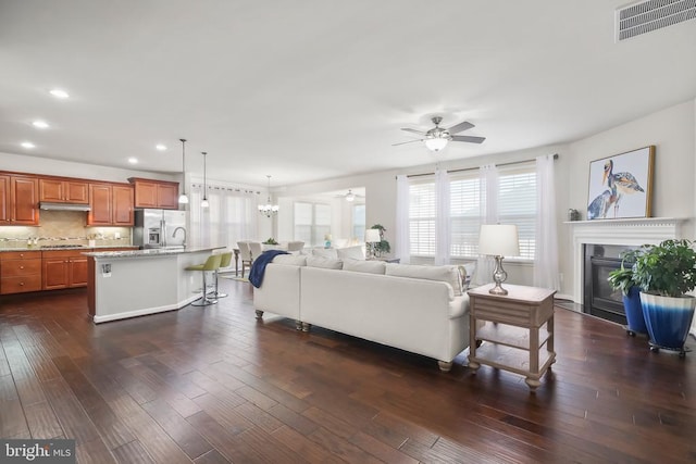 living room with dark hardwood / wood-style floors and ceiling fan with notable chandelier