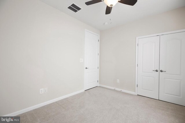 unfurnished bedroom with ceiling fan, light carpet, and a closet