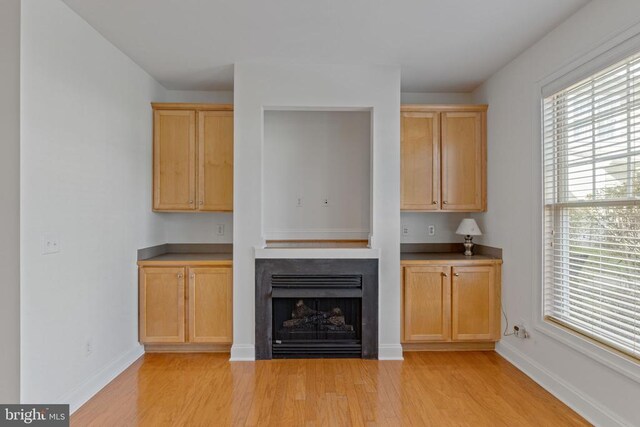 bar with light brown cabinetry and light wood-type flooring