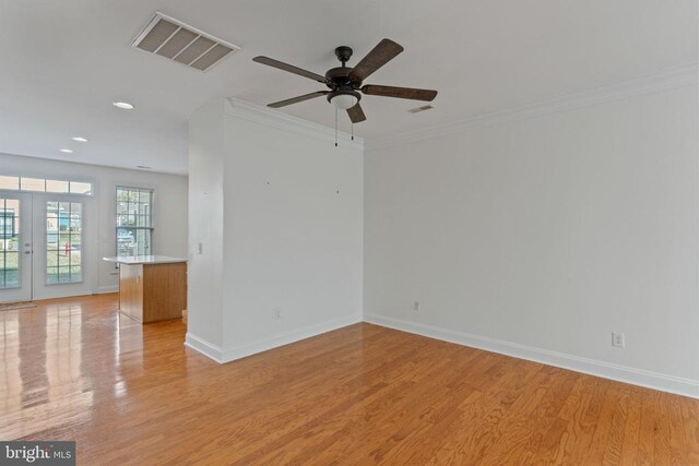 unfurnished room with ornamental molding, ceiling fan, light wood-type flooring, and french doors