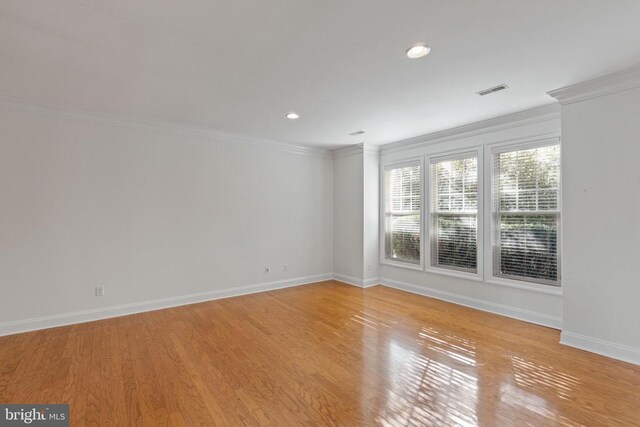 empty room with crown molding and light hardwood / wood-style floors