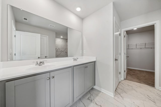 full bathroom with a spacious closet, marble finish floor, double vanity, and a sink