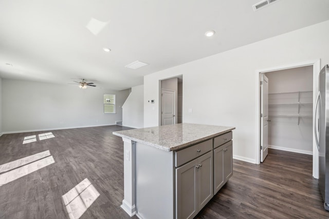 kitchen featuring a ceiling fan, baseboards, dark wood-style floors, a kitchen island, and gray cabinetry