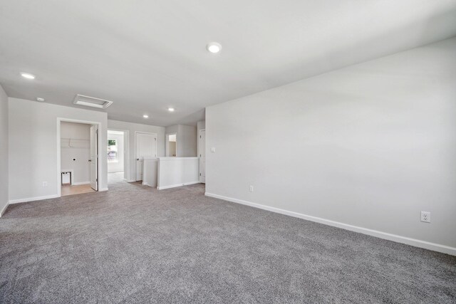 unfurnished living room with recessed lighting, baseboards, carpet floors, and attic access