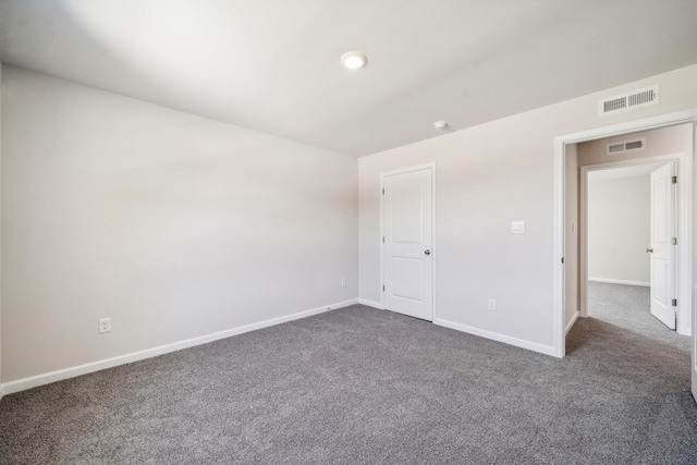 unfurnished bedroom with baseboards, visible vents, and dark carpet