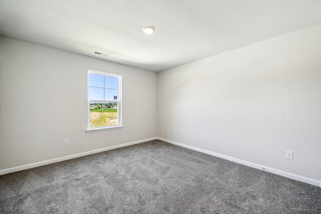 carpeted spare room featuring visible vents and baseboards