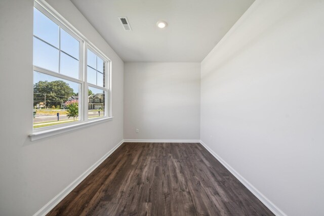 spare room with visible vents, baseboards, and dark wood-type flooring