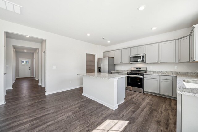 kitchen featuring visible vents, gray cabinetry, a kitchen island, dark wood-style floors, and stainless steel appliances