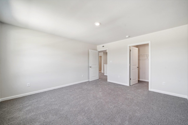 unfurnished bedroom featuring baseboards, carpet, and a spacious closet