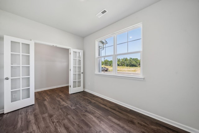 spare room featuring dark wood finished floors, french doors, visible vents, and baseboards