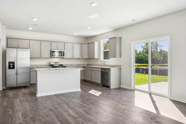 kitchen featuring recessed lighting, dark wood-style flooring, gray cabinetry, appliances with stainless steel finishes, and a center island