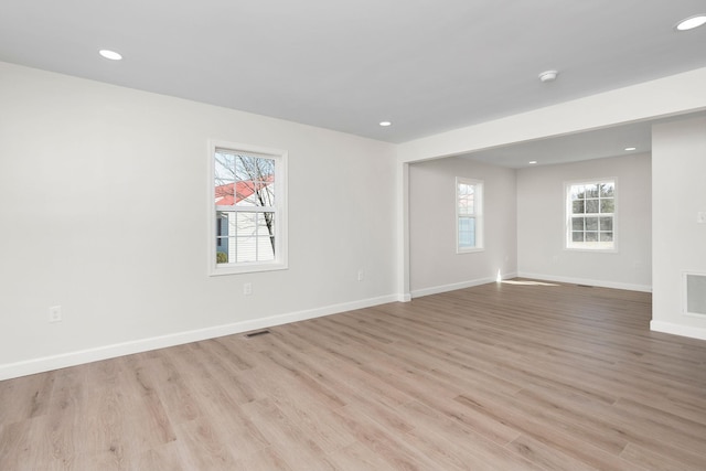 unfurnished room featuring plenty of natural light, baseboards, and light wood-style floors