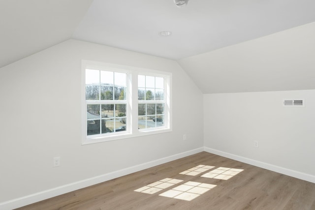 bonus room with visible vents, baseboards, wood finished floors, and vaulted ceiling