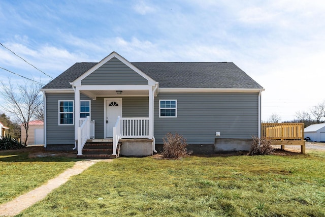 bungalow featuring a front yard, covered porch, and roof with shingles