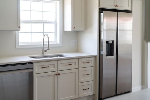 kitchen featuring light countertops, white cabinets, appliances with stainless steel finishes, and a sink