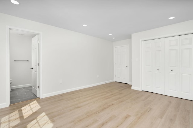 unfurnished bedroom with recessed lighting, light wood-style flooring, and baseboards