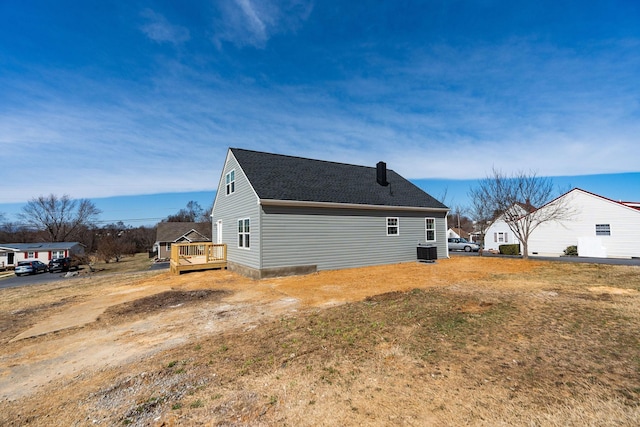 view of side of home with central air condition unit, a shingled roof, and a deck