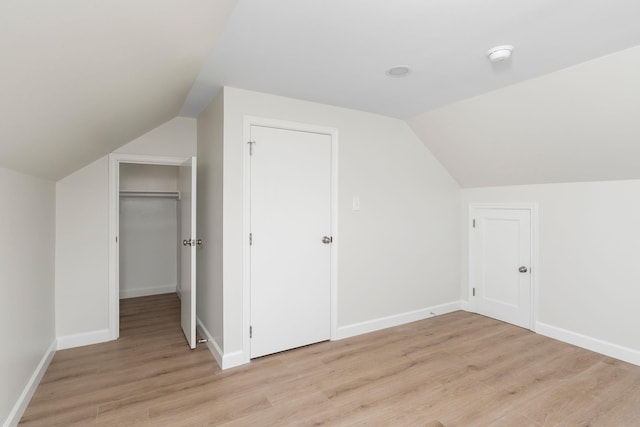 bonus room featuring lofted ceiling, light wood-style flooring, and baseboards